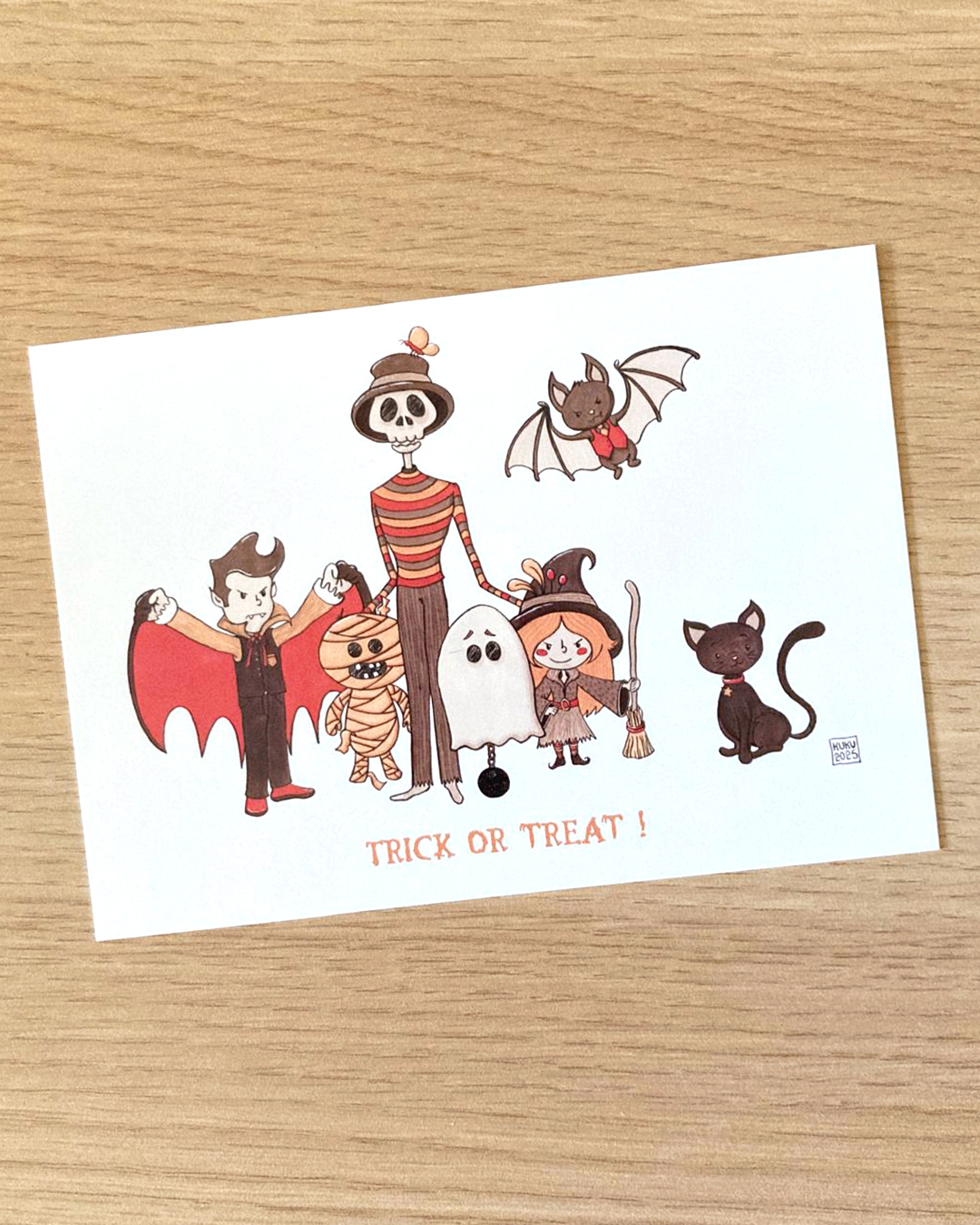 illustration d'halloween réprensentant un vampire, une momie, un squelette habillé, un fantôme, une sorcière, une chauve-souris et un chat noir avec la phrase "trick or treat!"