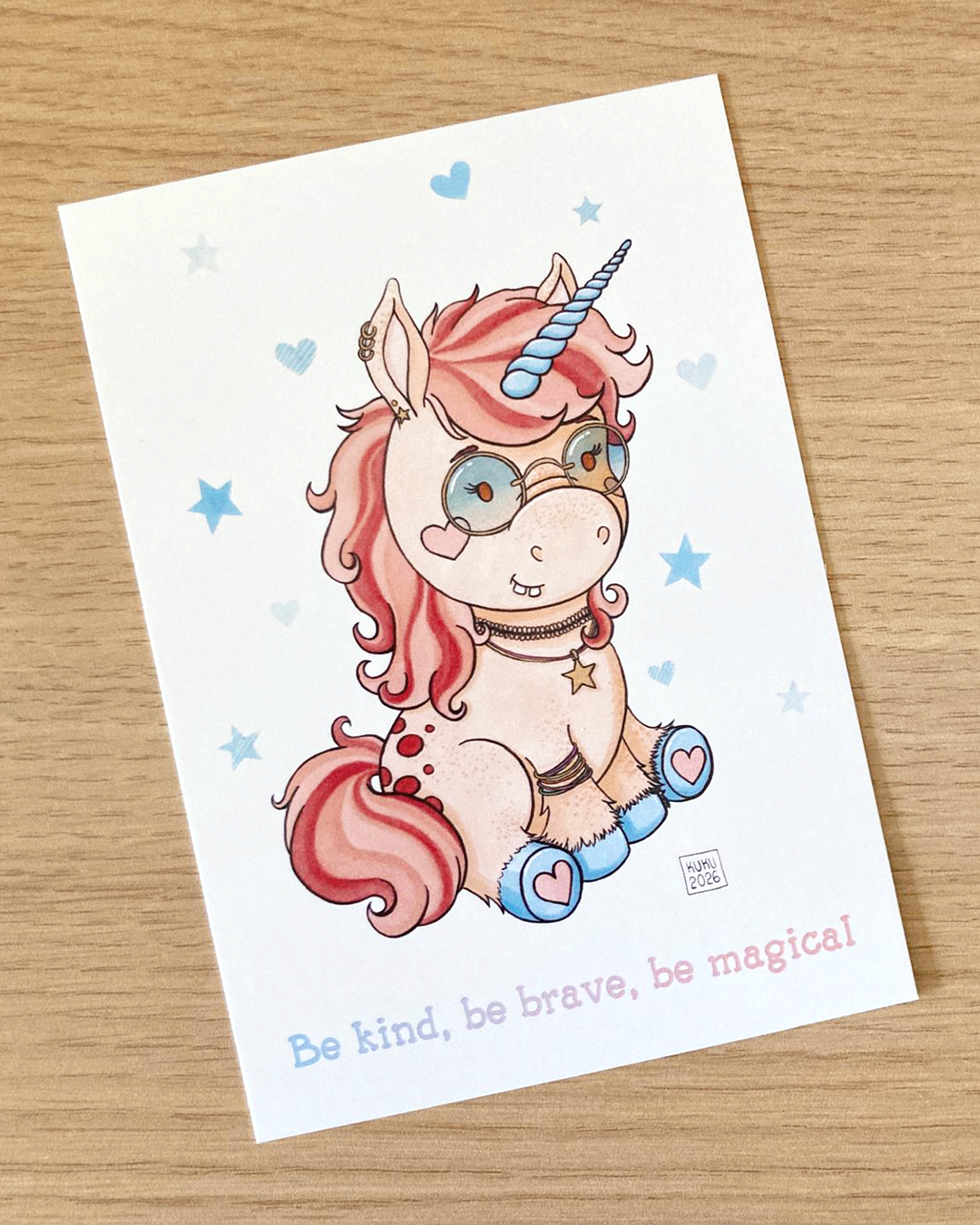 illustration d'une licorne portant des lunettes teintées et des piercing et bijoux avec la phrase "be kind, be brave, be magical"