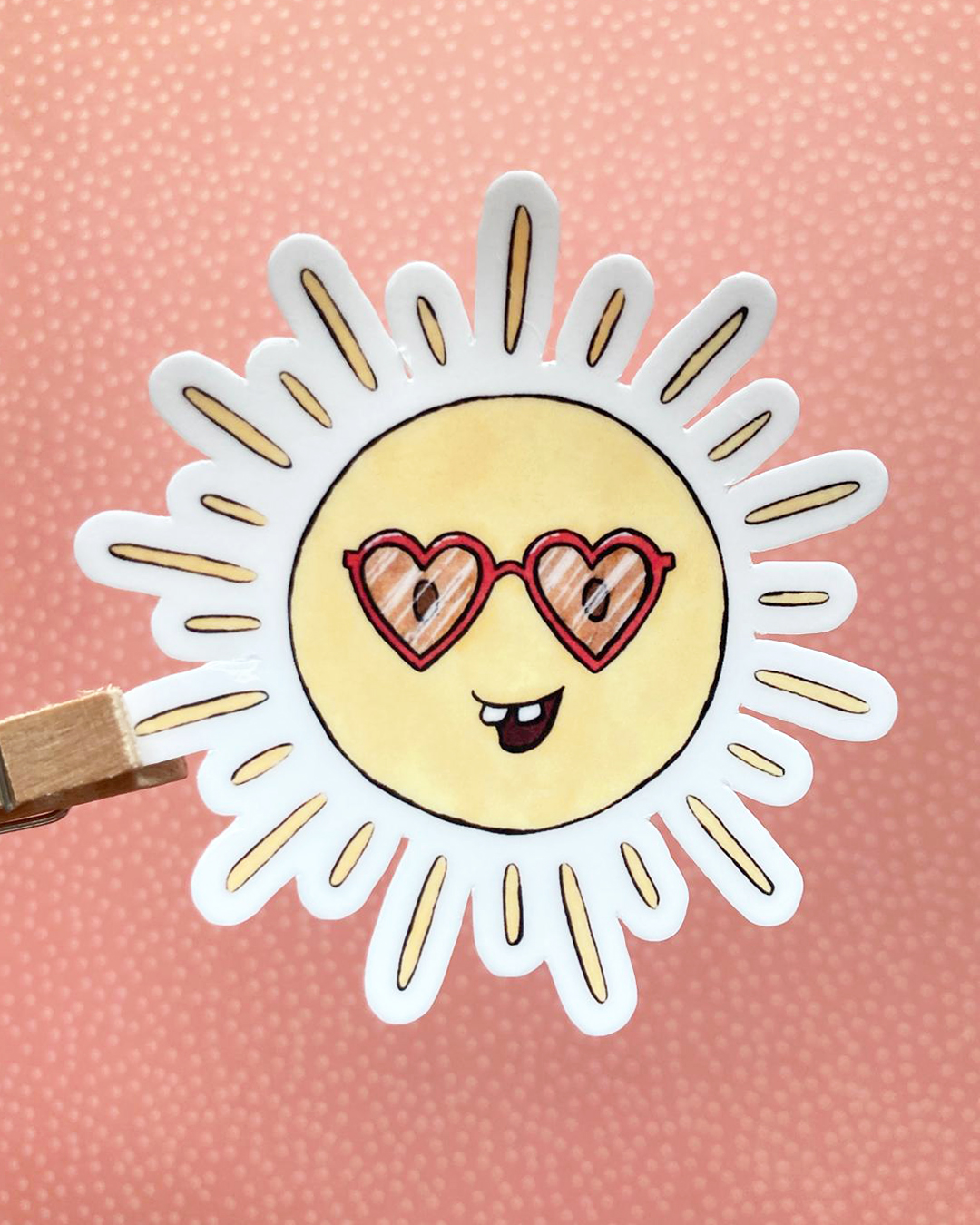 photo dqui représente un sticker en forme de soleil qui porte des lunettes rouges en forme de coeur